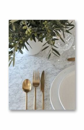 Elegant Dining Table Setting with Olive Branch Centerpiece and Golden Cutlery for a Festive Occasion
