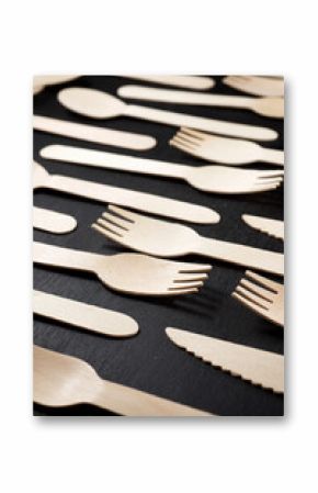 Disposable wooden cutlery on a black table.