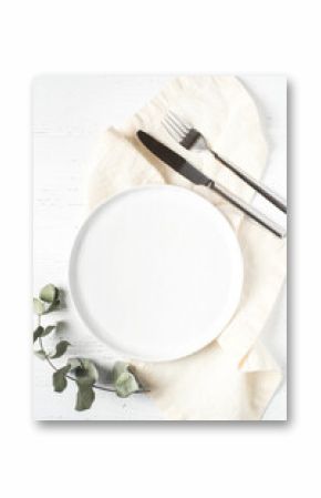 An empty plate and cutlery on a white wooden table. Top view.