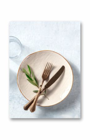 A plate with cutlery and a glass, with an olive branch, shot from the top. Mediterranean cuisine restaurant concept. Trendy tableware, shot from above