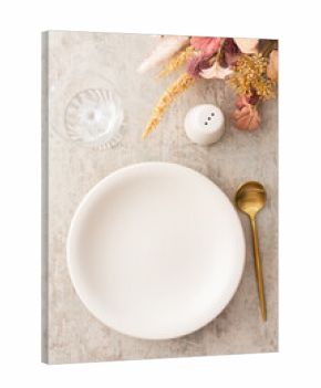 Table setting, plate and golden cutlery on a brown background, empty wine glass, top view of the served table decorated with dry flowers