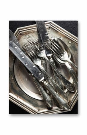 Antique silver cutlery on a dark background in a composition on a table.