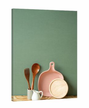 Kitchen ceramic dish plate, coaster, cutlery holder on wooden shelf. green wall background