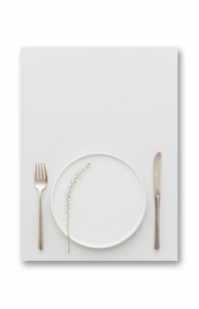 Minimal grey and white table setting with a brass cutlery set, a plate decorated with greenery.