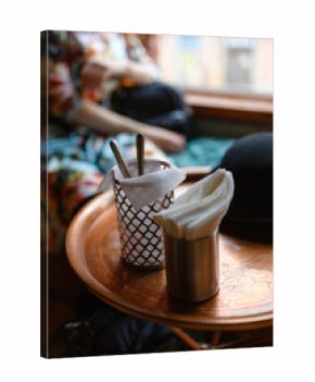 Cutlery on a wooden table in a cafe, napkins in an iron glass. Table settings with glasses, napkins and cutlery on a wooden table.