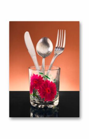 Glass with flowers design and cutlery set in it