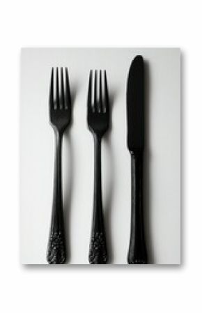 Elegant, matte-black cutlery set including two forks and a knife on white
