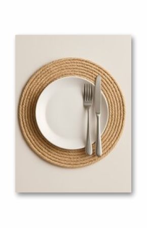Elegant dinner setting with a rope placemat featuring white plate and silver cutlery
