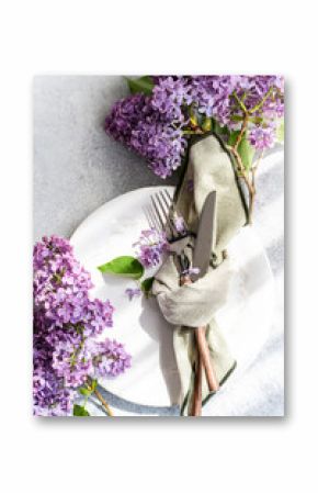 Overhead view of a springtime place setting with purple lilac flowers on a table