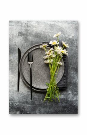 Daisy arrangement on concrete with cutlery and plates