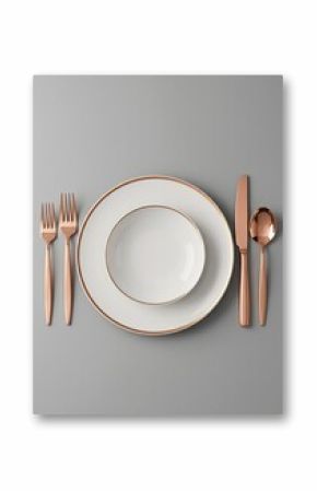 Photo of an elegant dinner arrangement displays white plates and a bowl with rose gold accents alongside matching cutlery presented on a plain gray surface