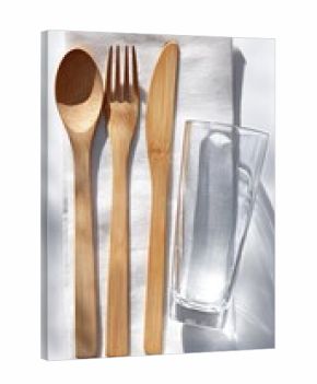 Minimalist bamboo cutlery set alongside a glass, arranged on a folded white cloth, casting soft shadows
