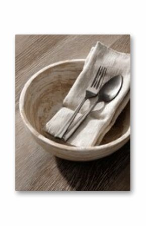 A rustic wooden bowl, paired with silverware on a linen cloth, sets a scene of elegant simplicity.