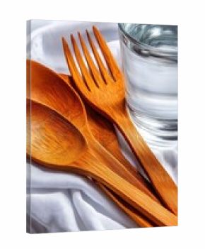 Wooden spoons and fork on a white cloth, with a glass of water