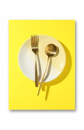 Stylish plate and cutlery on yellow background, top view