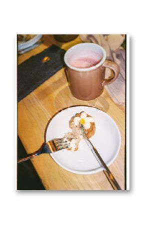 Film closeup photo of cute desert on a plate, torn by fork and a knife