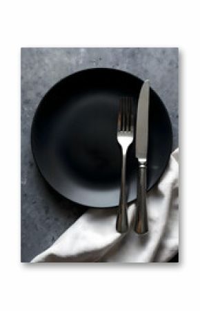 Elegant table setting with black plate, fork and knife placed on marble and stone background, minimalistic dining concept with modern cutlery and clean design for stylish restaurant or home interior