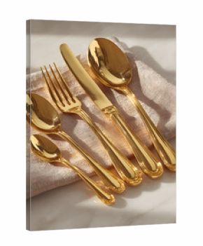 Gold-colored cutlery set arranged on a pale pink fabric.