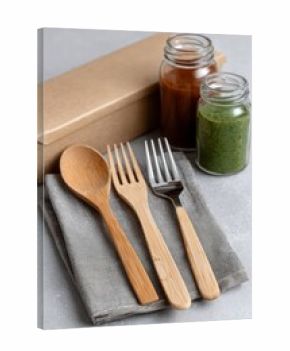 Eco bamboo and steel cutlery set with glass jars and sauces, sustainable dining lifestyle flat lay