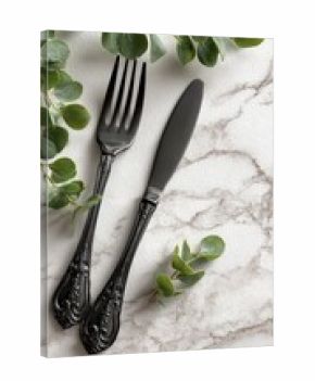 Black cutlery on marble with greenery