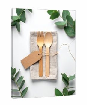 Wooden spoon and fork on linen napkin, framed by eucalyptus leaves, with a blank tag