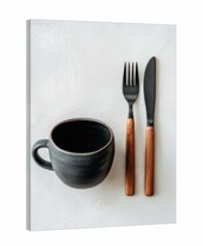 Dark gray ceramic mug, black cutlery with light brown handles on a light gray surface