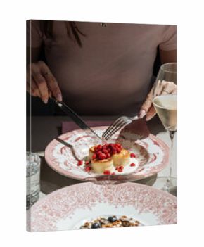 Woman cutting cottage cheese pancakes with wild strawberries and sour 
