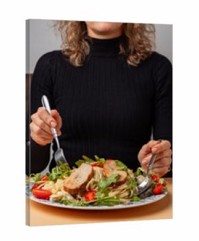 Pasta with shrimps, arugula and tomatoes isolated. Female hands with cutlery