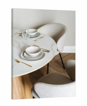 Elegant white dish setting with cutlery on a marble dining table in a modern space