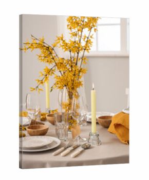 Elegant table setting with clean plates, burning candles, cutlery and blooming tree branches