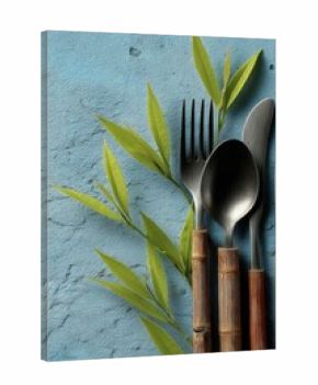 Eco-friendly cutlery and leaves on textured blue background for sustainability concept