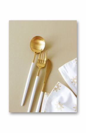 Modern gold cutlery and festive napkin top view on beige background. Christmas table setting .copy space .