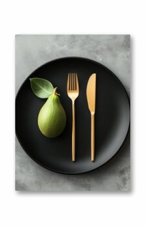 Elegant pear with gold cutlery on black plate for modern dining concept