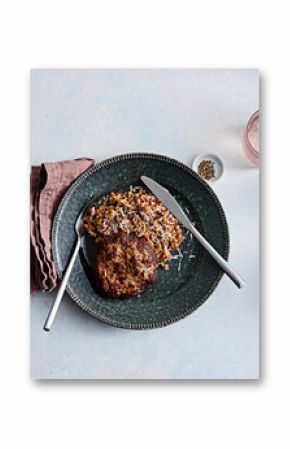 A flavorful meat patty is paired with a hearty serving of healthy buckwheat on a rustic plate. The meal is complemented by simple cutlery and a soft linen napkin, creating a warm dining experience