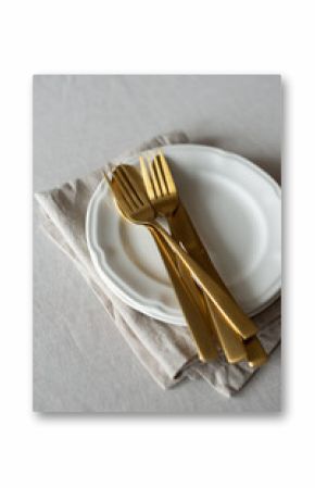 Golden cutlery with beige cotton napkins on the table. Knives, spoons and forks on a neutral cotton tablecloth. Table setting in a minimalist style