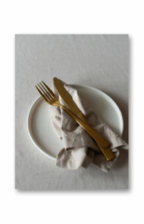 Golden cutlery with beige cotton napkins on the table. Knives, spoons and forks on a neutral cotton tablecloth. Table setting in a minimalist style
