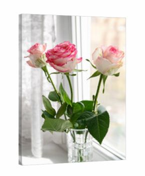 Bouquet of three pink roses in vase stands on windowsill