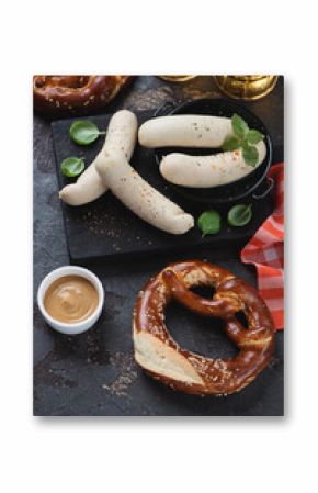 Black wooden serving board with german white sausages, pretzels and beer, vertical shot on a brown stone background