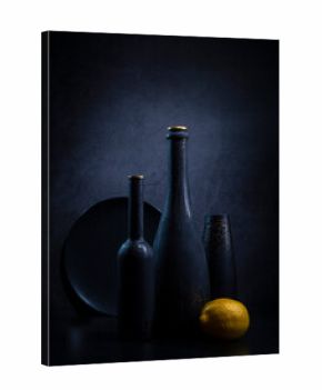 Modern still life with black bottles and lemon in blue tones