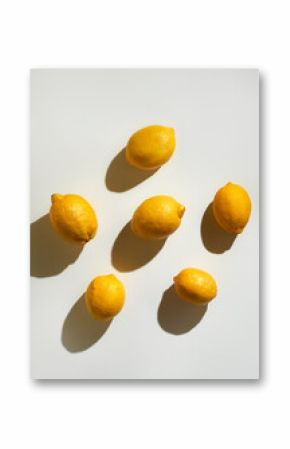 Yellow juicy lemons making pattern on white backdrop under sunlight