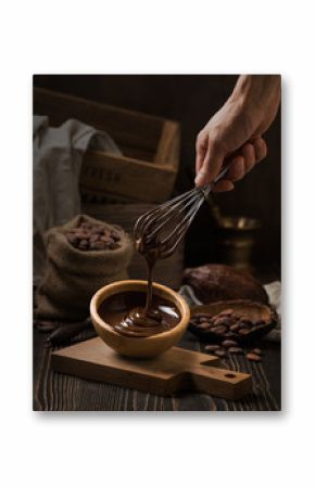 Dark still life with melted chocolate in wooden bowl