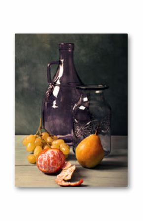 Still life with blue glass vase, lilac glass jar and fruit on turquoise background