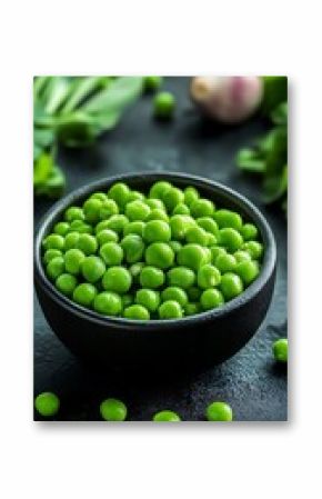 Fresh Green Peas in Dark Bowl with Garlic and Greens on Black Background