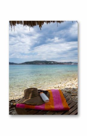 Sunscreen, Hat, and Towel on a Lounger at a Pebble Beach