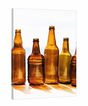 Five amber and brown glass bottles arranged vertically against a bright window background