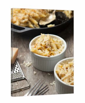 High angle close up of two ramekins and a dish with mac and cheese, cheese sauce and macaroni.