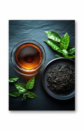Glass cup of tea with dried tea leaves and fresh green tea leaves on black background