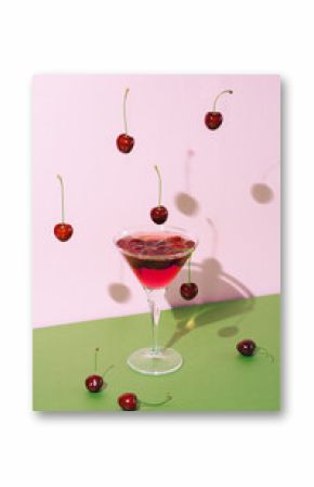 Abstact summer refreshment concept with cocktail glass with shadow and cherry fruit falling from above