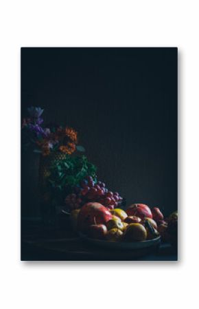 Dark baroque renaissance style still life photography of fruit and flowers. Apples, grapes, pomegranate, quince, mint and garden flowers.