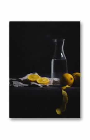 Still life with lemons, water and linen against a dark background